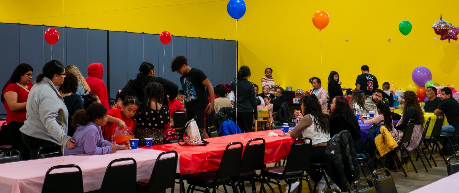 Kids around a decorated birthday table in the party room at People's Choice